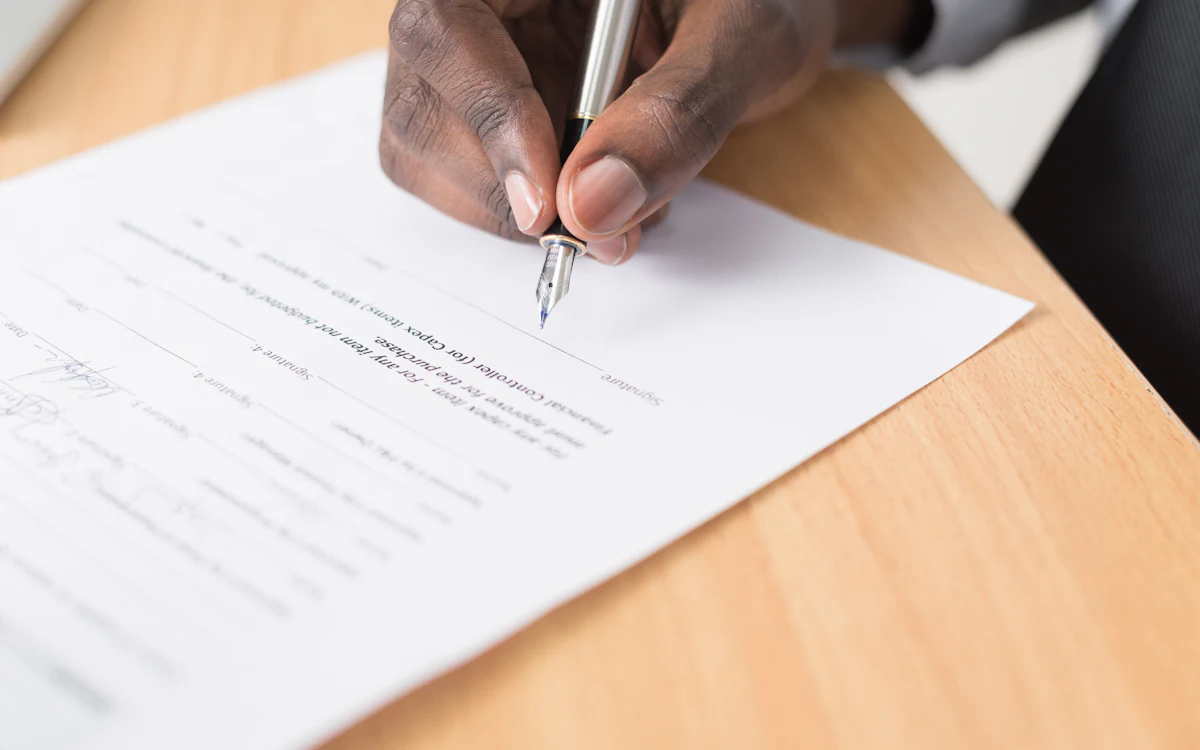 Una persona revisa y firma documentos sobre una mesa
