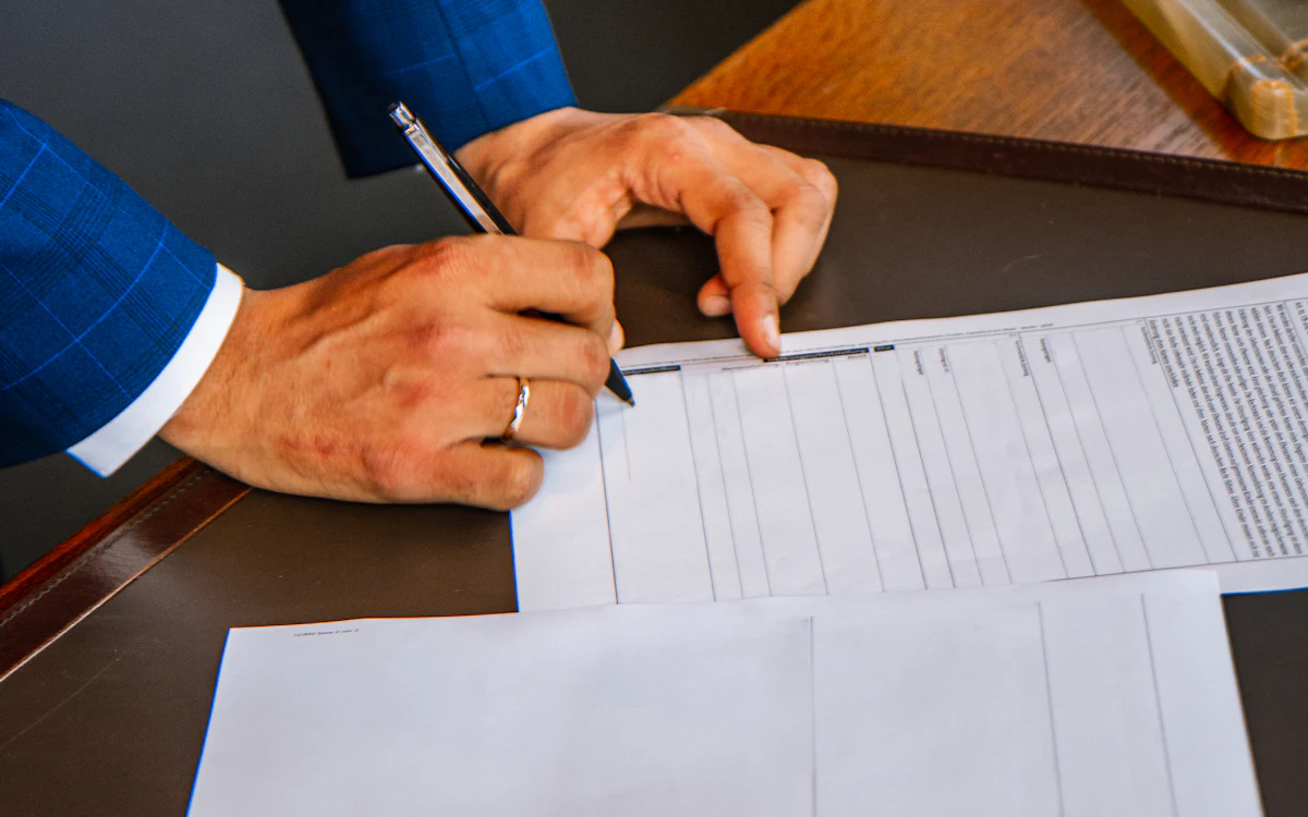 Una persona llena a mano un formulario impreso sobre un escritorio