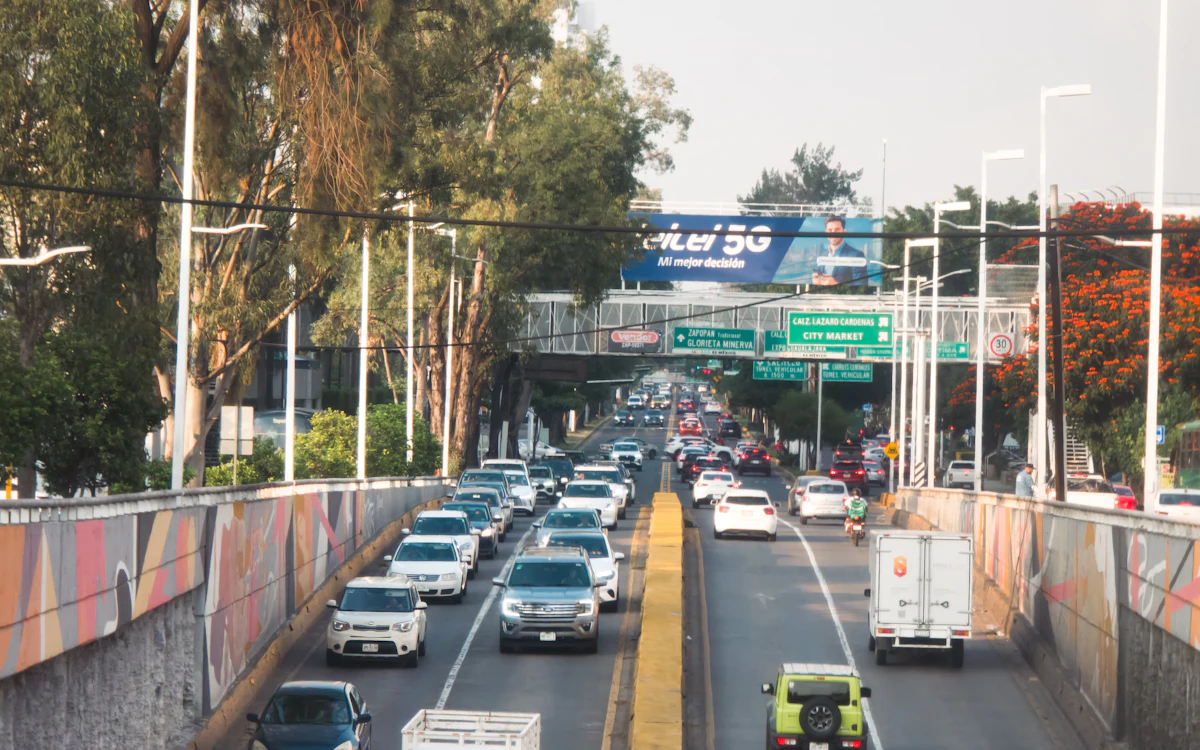 Tráfico intenso en una avenida de varios carriles con árboles en Guadalajara