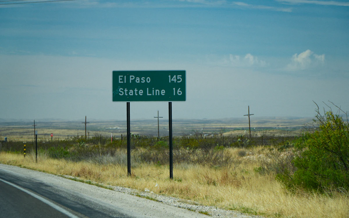 Letrero de carretera que indica El Paso y la línea estatal en un paisaje desértico